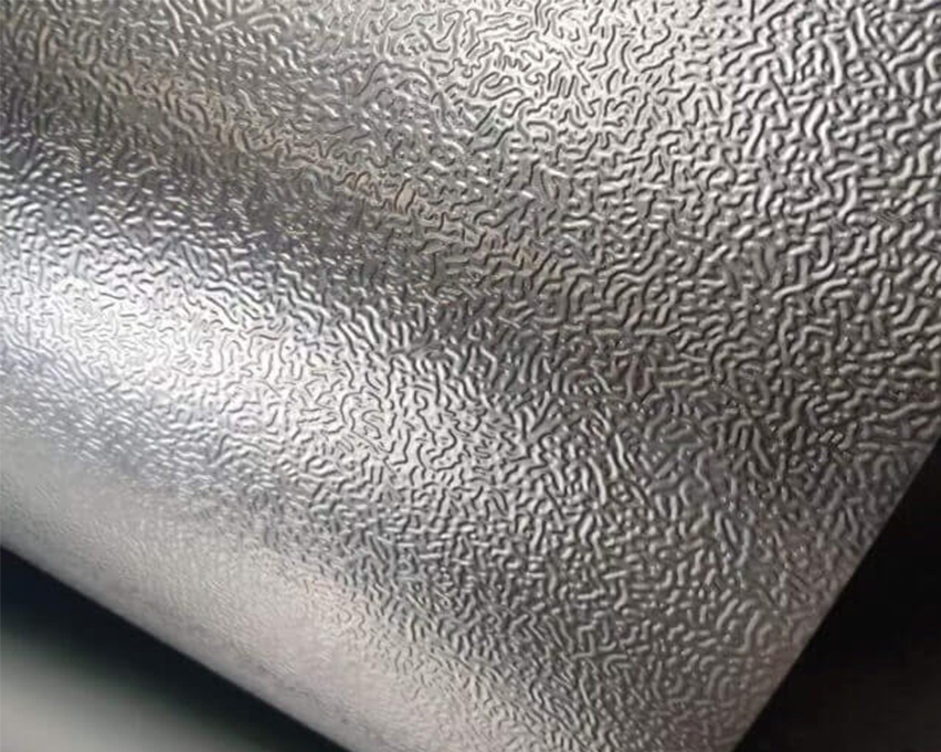 Gros plan d’une tôle aluminium gaufrée aux petits reliefs sinueux et aux reflets argentés