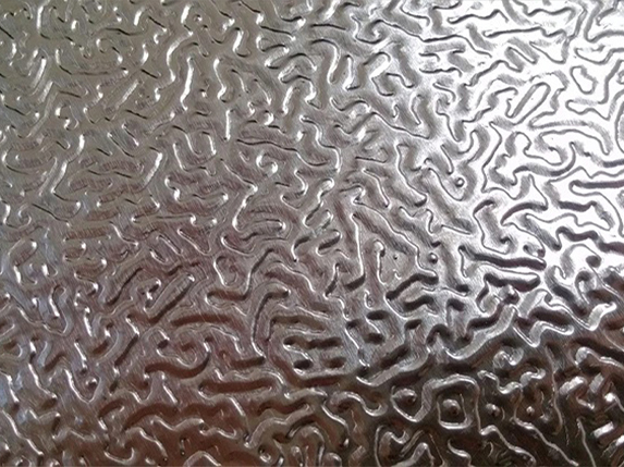 Surface argentée d’une tôle aluminium gaufrée avec des motifs sinueux en relief